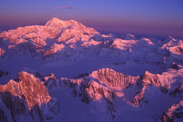 Mountain range with pink sunset glow on snow-covered peaks.