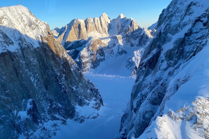Snow-covered mountain range with a glacier under a clear blue sky.
