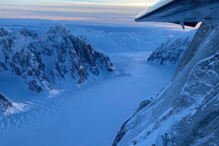 Snowy mountain landscape viewed from airplane wing perspective.