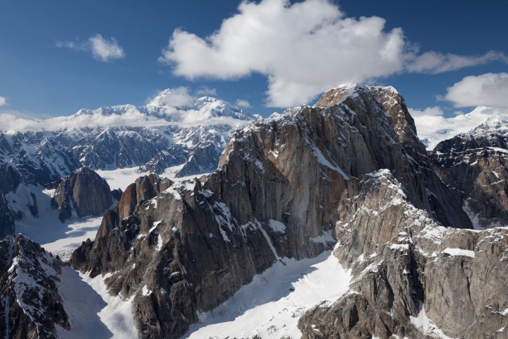 Snow-covered mountains under a blue sky with clouds.